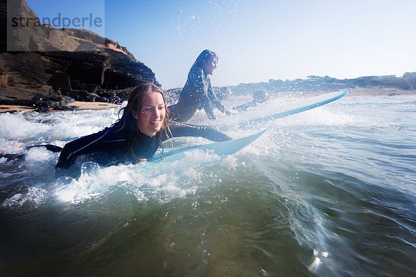 Vier Leute im Wasser mit lächelnden Surfbrettern.