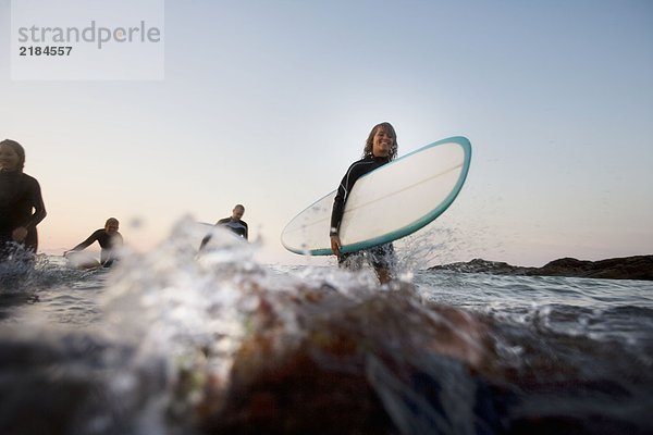 Vier Leute mit Surfbrettern im Wasser.