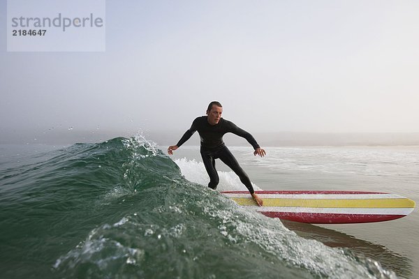 Ein Mann  der auf einer Welle surft.