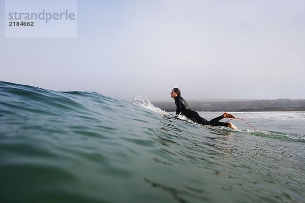 Ein Mann  der auf einem Surfbrett im Wasser steht.