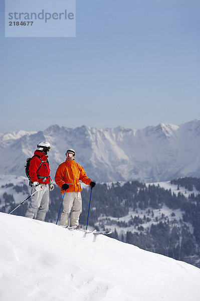 Österreich  Saalbach  zwei Skifahrer stehen auf der Piste und reden miteinander.