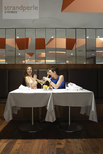 Zwei Frauen in einem Restaurant mit einem Löffel auf der Nase
