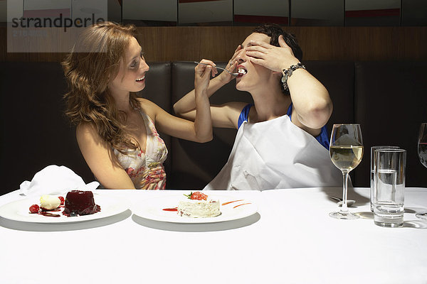 Zwei Frauen in einem Restaurant  die sich gegenseitig füttern.