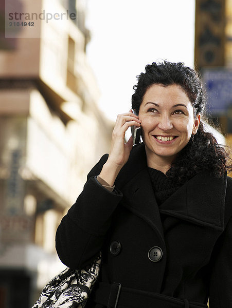 Frau auf der Straße stehend mit dem Handy  lächelnd