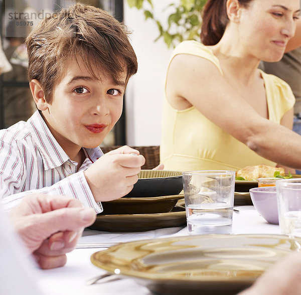 Junge (4-6) beim Essen mit der Familie  lächelnd  Portrait