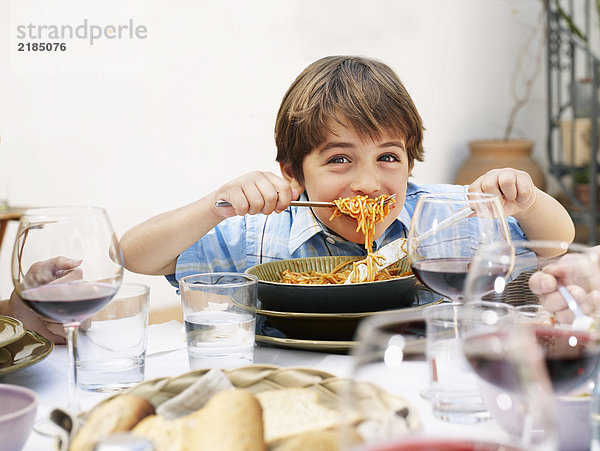 Junge (4-6) isst Spaghetti  lächelnd  Portrait