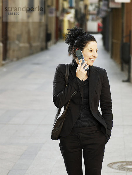Junge Frau auf der Straße mit dem Handy  lächelnd