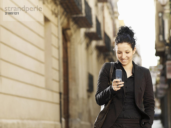 Junge Frau auf der Straße mit dem Handy  lächelnd