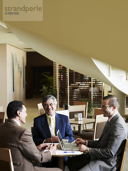 Drei Geschäftsleute  die sich im Restaurant treffen  lächelnd