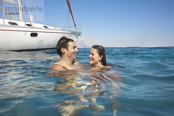 Junges Paar  das mit einer Yacht im Meer schwimmt  lächelnd