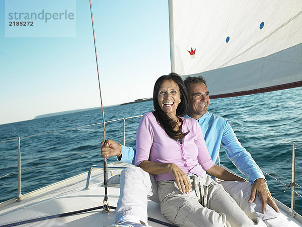 Erwachsenes Paar auf dem Deck der Yacht sitzend  lächelnd  Portrait