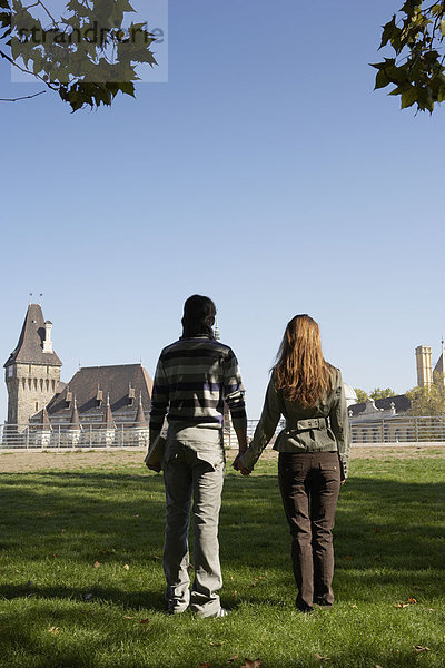 Ein Paar hält sich an den Händen in einem Park.
