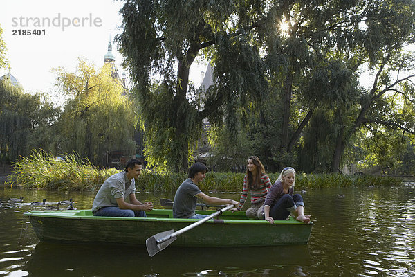 Vier Freunde in einem Ruderboot lächeln.