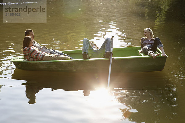 Vier Freunde in einem Ruderboot lächelnd und entspannend.