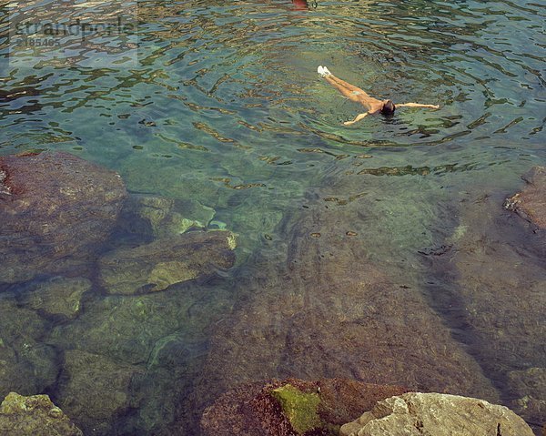 Eine Frau  die auf ihrem Rücken im Wasser schwimmt.