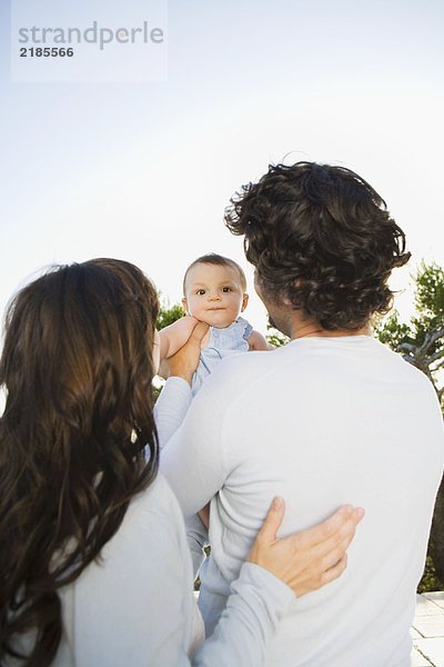 Ein Paar hält ein Baby im Freien.