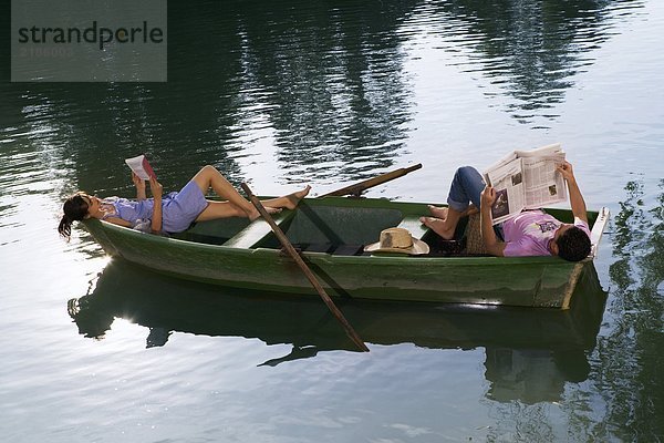 Mann und Frau liegend und lesend in einem Boot
