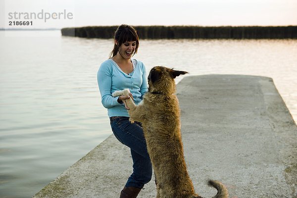 Mädchen spielt mit Hund am See.