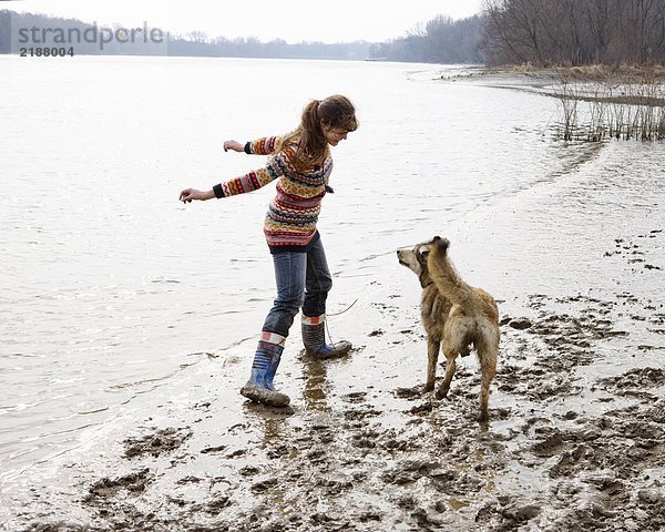 Junge Frau spielt mit Hund am Fluss