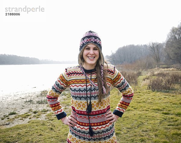 Junge Frau mit Hut am Fluss stehend  lächelnd  Portrait