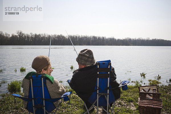 Seniorenpaar beim gemeinsamen Angeln am Fluss  Rückansicht