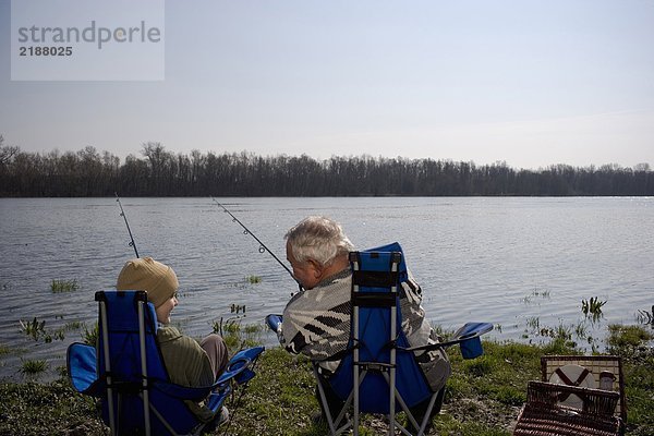 Großvater und Enkel (12-14) beim Angeln am Fluss  Rückansicht