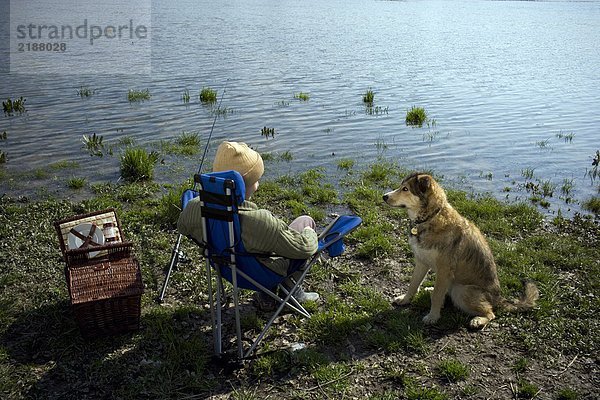 Junge (12-14) Angeln am Fluss mit Hund  Rückansicht