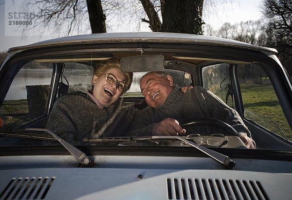 Seniorenpaar im Auto sitzend  lachend  Blick durchs Fenster