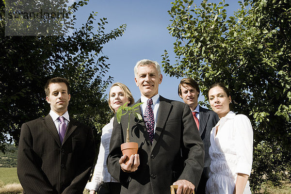 Gruppe von Geschäftsleuten in einem Obstgarten.