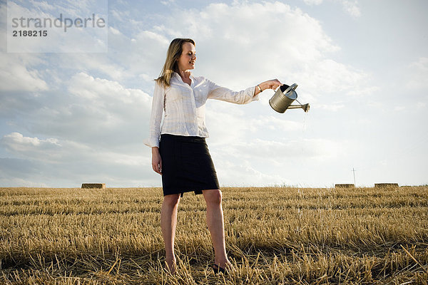 Frau gießt Wasser auf das Weizenfeld.