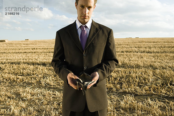 Mann mit leerer Brieftasche im Weizenfeld.