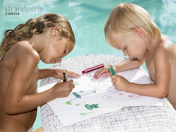 Zwei kleine Kinder beim Malen am Pool.