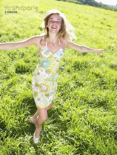 Junge Frau tanzt auf der grünen Wiese.