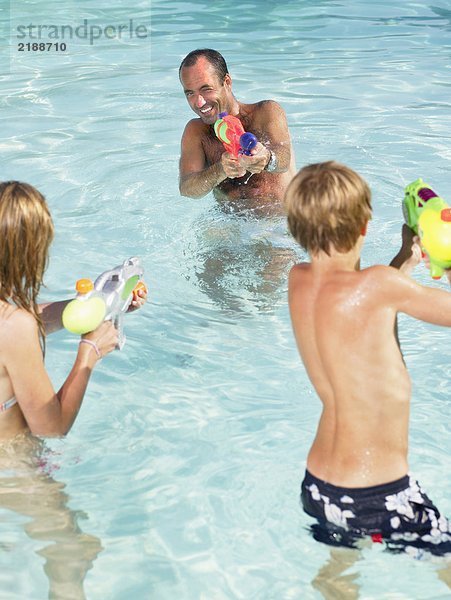 Kinder und Erwachsene spielen mit Wasserpistolen.