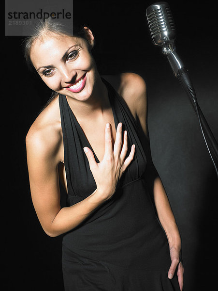 Sängerin mit Mikrofon elegantes schwarzes Kleid Portrait.