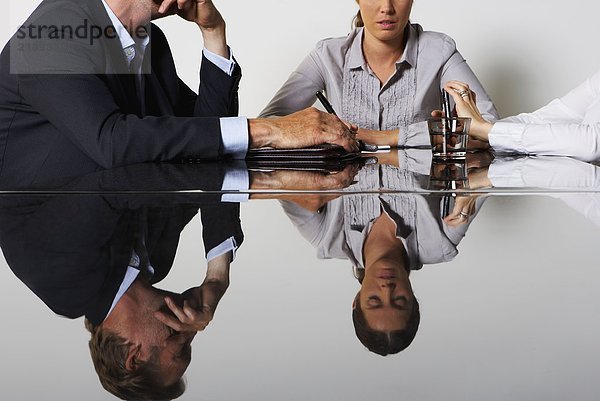 Das Spiegelbild von drei Geschäftsleuten in einem Tisch.