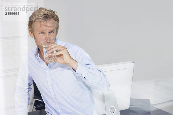 Mann im Büro Trinkwasser mit Spiegelungen.