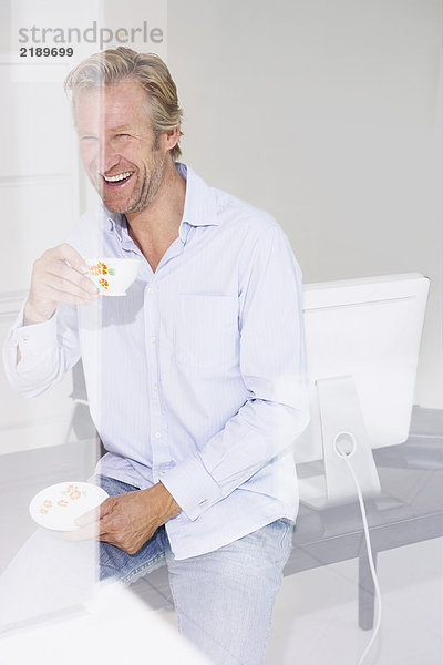 Mann im Büro mit einer Tasse Tee  lächelnd mit Reflexionen.