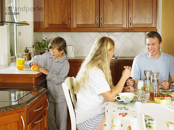 Familie beim Frühstücken in der Küche lächelnd.