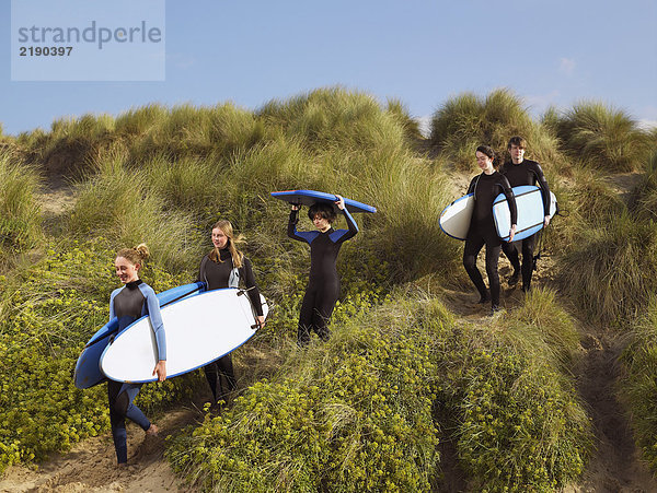 Fünf Teenager  die mit Surfbrettern laufen.