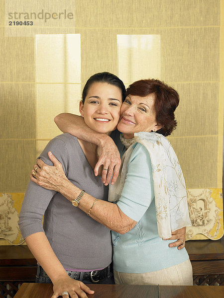 Seniorenmutter umarmt Tochter  lächelnd  Portrait