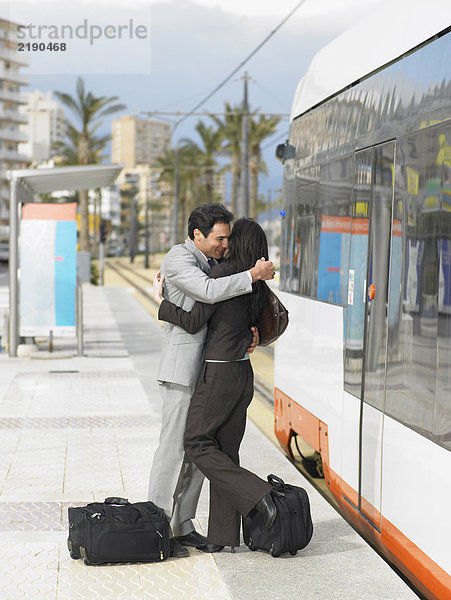Geschäftsmann und Geschäftsfrau mit der Straßenbahn umarmend