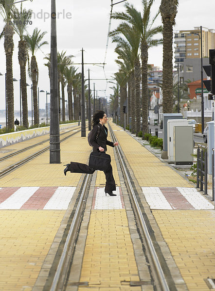 Geschäftsfrau  die mit der Straßenbahn über den Fußgängerüberweg rennt.