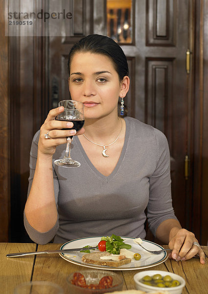 Junge Frau bei einem Glas Rotwein zum Mittagessen  lächelnd  Portrait