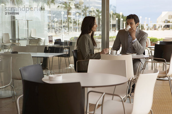 Geschäftsmann und Geschäftsfrau sitzen vor dem Café und trinken Kaffee. Alicante  Spanien.