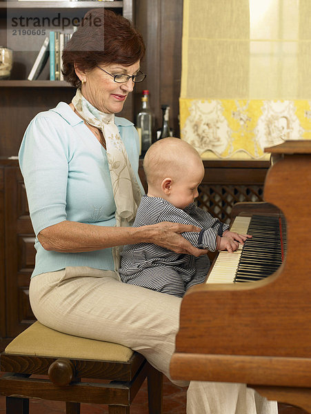 Senior Großmutter spielt Klavier mit Enkelkind (1-3 Monate)
