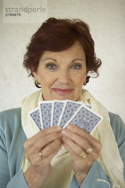 Seniorin mit Spielkarten  lächelnd  Portrait