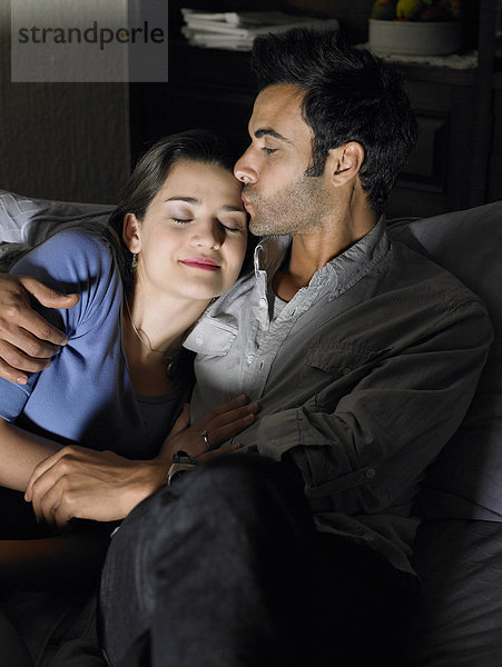 Junges Paar entspannt auf Sofa  Mann küsst Frau