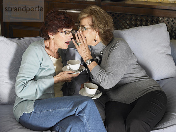 Zwei ältere Frauen klatschen über eine Tasse Tee auf dem Sofa. Alicante  Spanien.