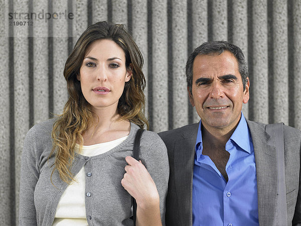 Kopf und Schultern Porträt eines älteren Mannes und einer jungen Frau in Geschäftsanzügen mit Blick in die Kamera gegen strukturierten Beton  Alicante  Spanien